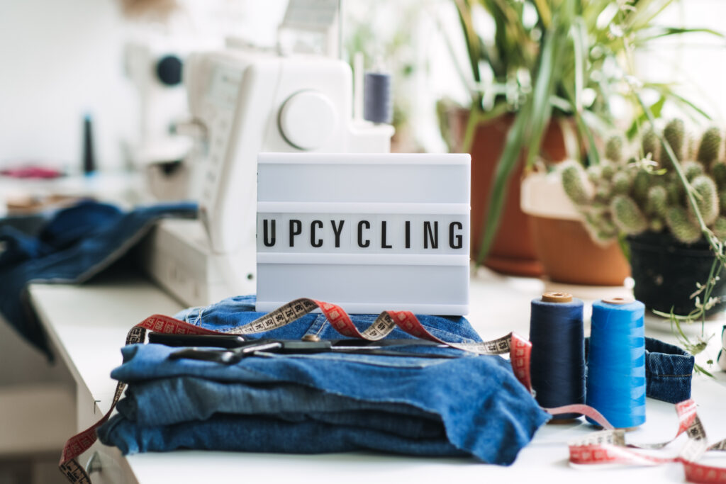 Caja de letras con la palabra Upcycling escrita, sobre un montón de retales de tela denim en un taller de costura.