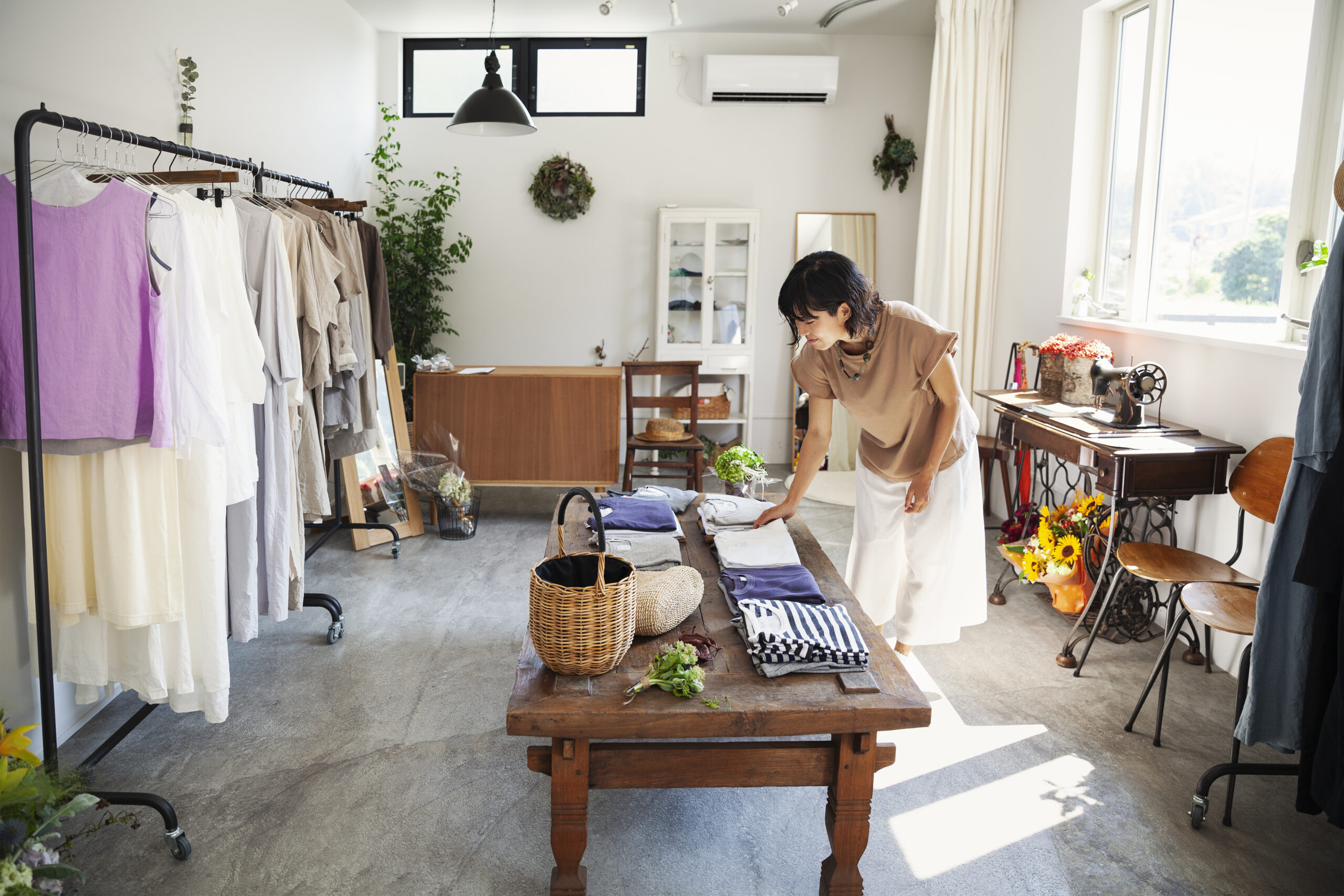 Mujer en una pequeña boutique de moda, mirando camisetas en una mesa de café.